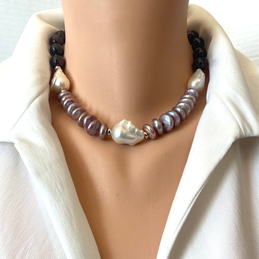 A close-up of a double-strand pearl necklace displayed on a mannequin torso wearing a white collared shirt. The necklace features dark brown beads on one side, iridescent baroque pearls on the other, and a central large white baroque pearl.