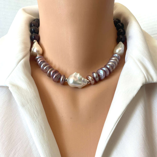 A close-up of a double-strand pearl necklace displayed on a mannequin torso wearing a white collared shirt. The necklace features dark brown beads on one side, iridescent baroque pearls on the other, and a central large white baroque pearl.