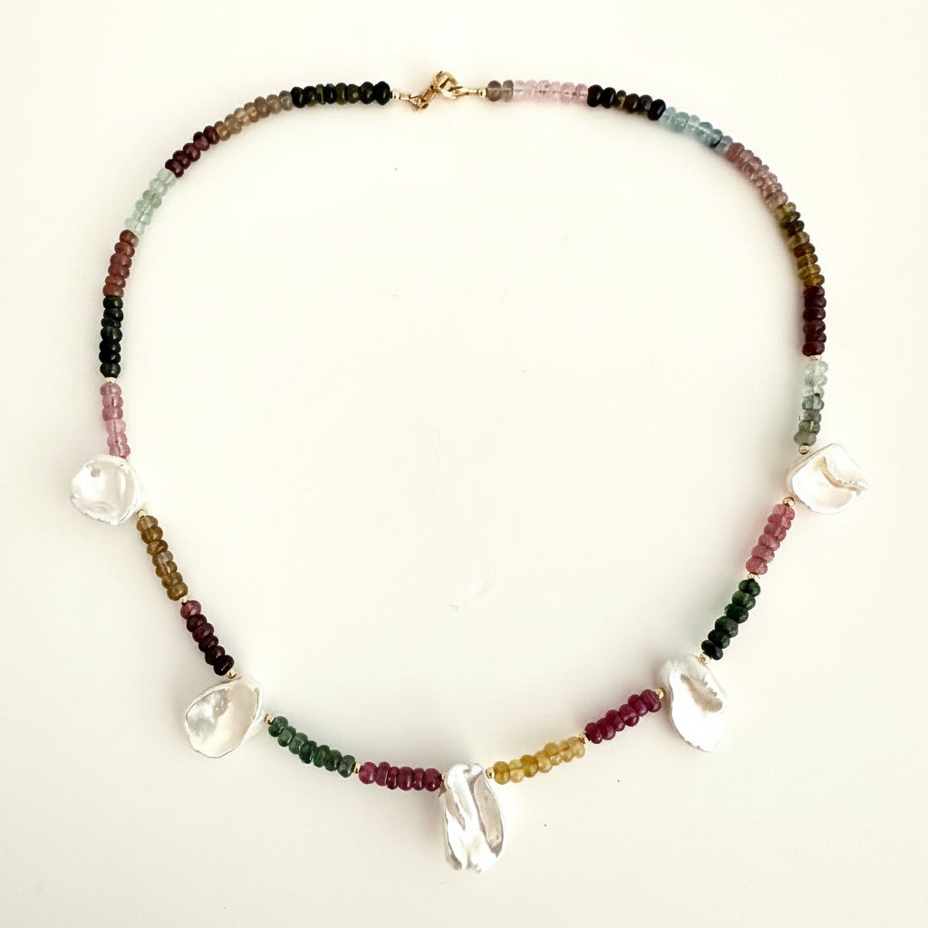 A beaded necklace with small multicolored tourmaline beads and 5 white pearl charms, displayed on a plain off-white background.