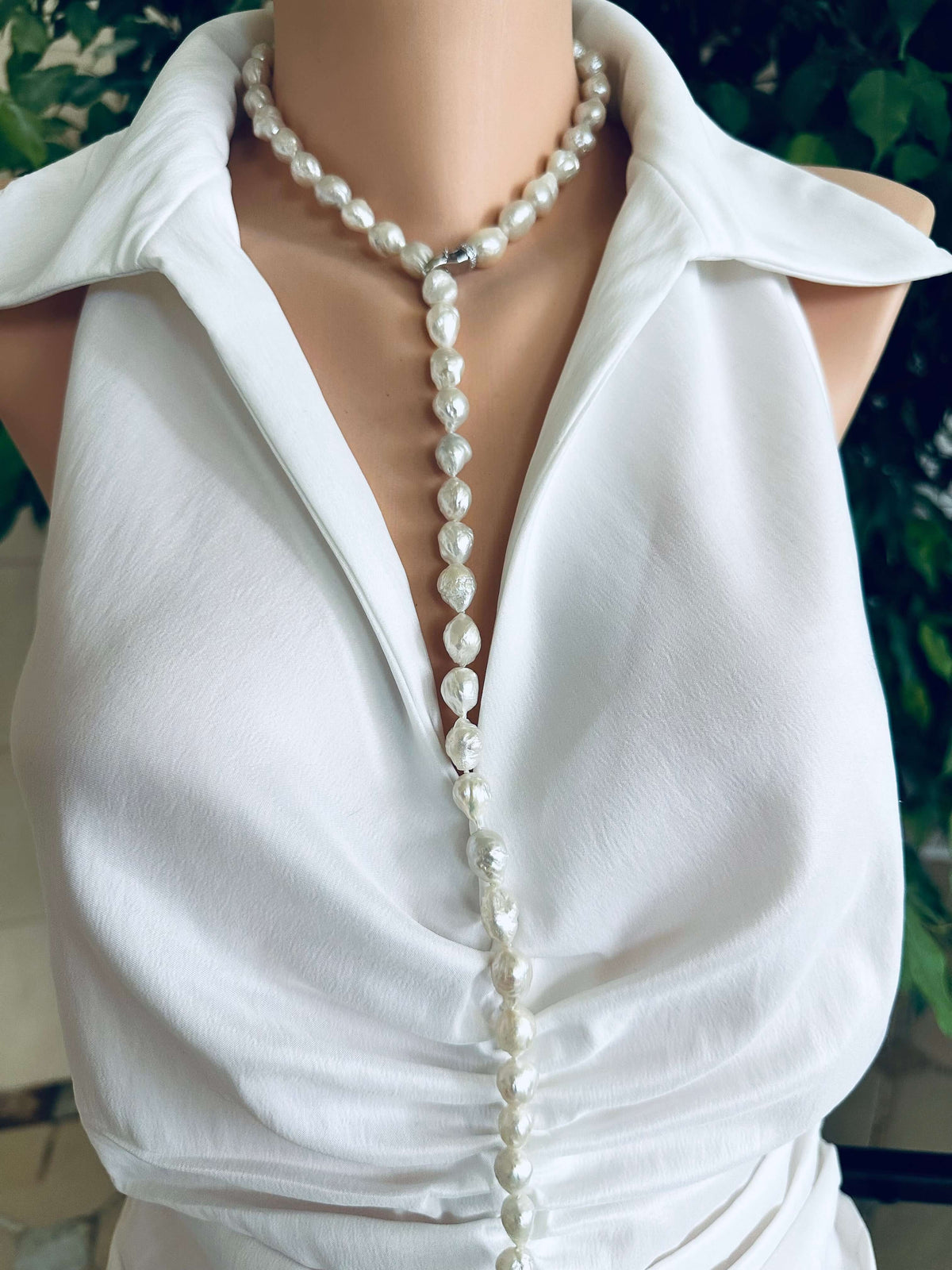 Edison baroque pearl Y necklace displayed on mannequin, featuring hand knotted white avocado pearls and rhodium clasp.