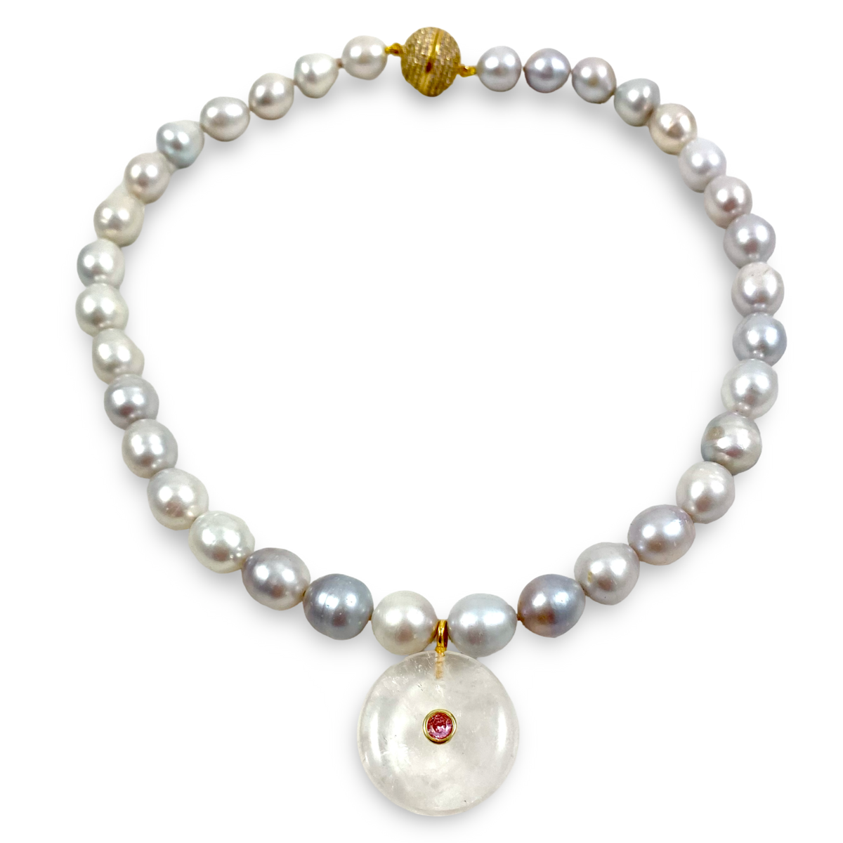 A pearl necklace with irregular white and gray pearls, accented by a gold clasp, a gold bead, and a large round white stone pendant featuring a small red gemstone, shown on a plain white background.