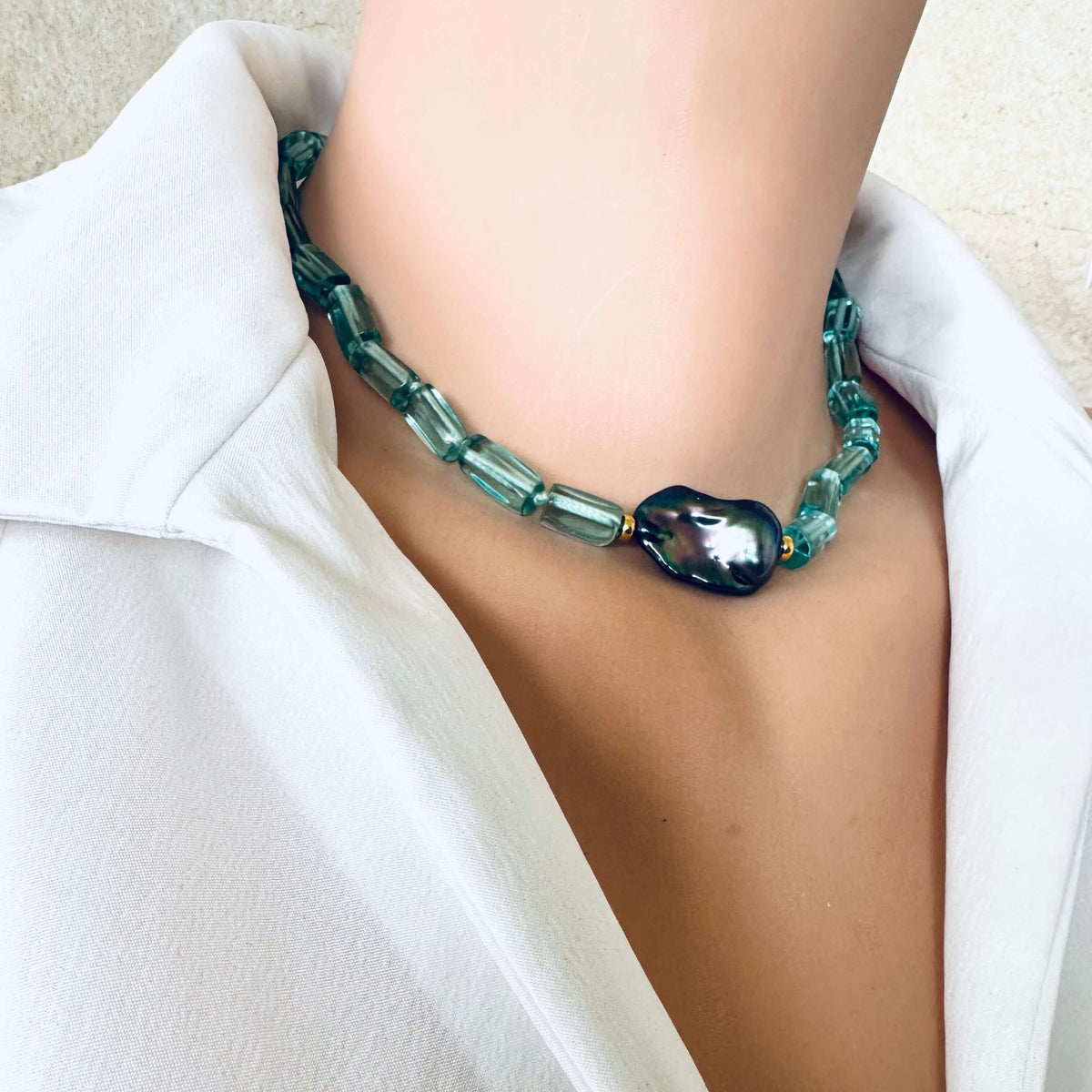 Green beaded necklace worn by a person in a white outfit