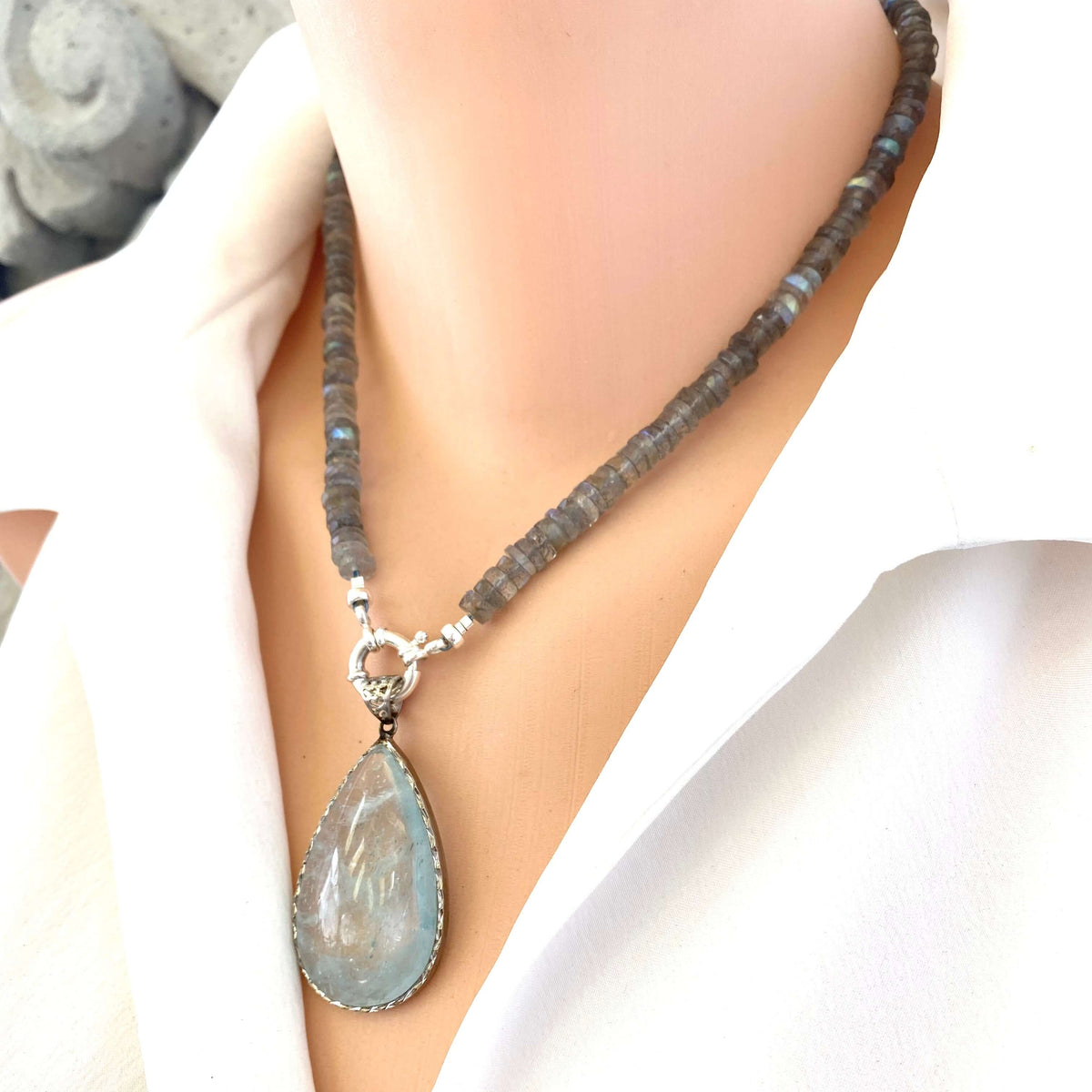 Aquamarine teardrop pendant in oxidized sterling silver worn on a short necklace, highlighting its blue tones and artisan design.