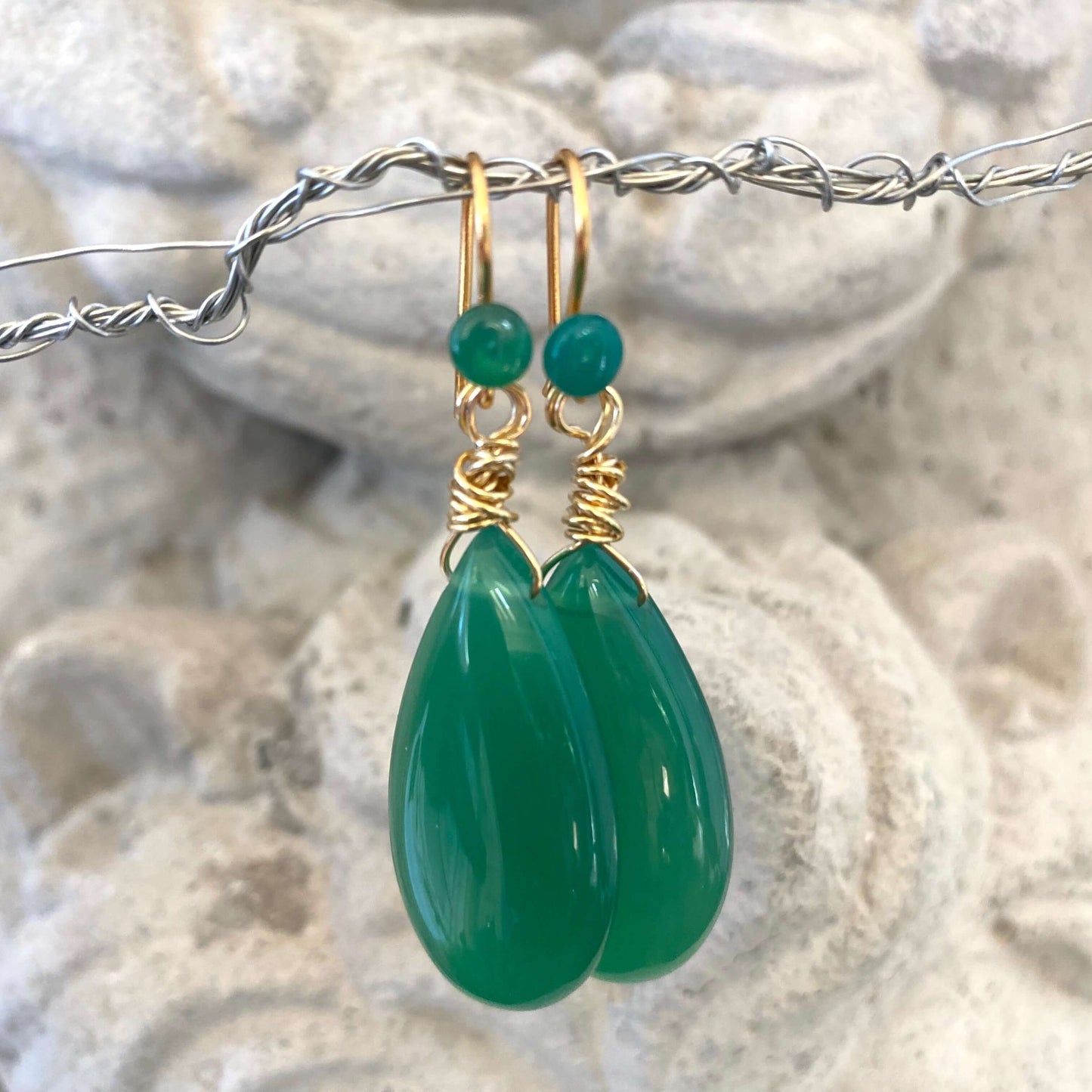 Emerald green onyx teardrop earrings photographed close up with gold plated details
