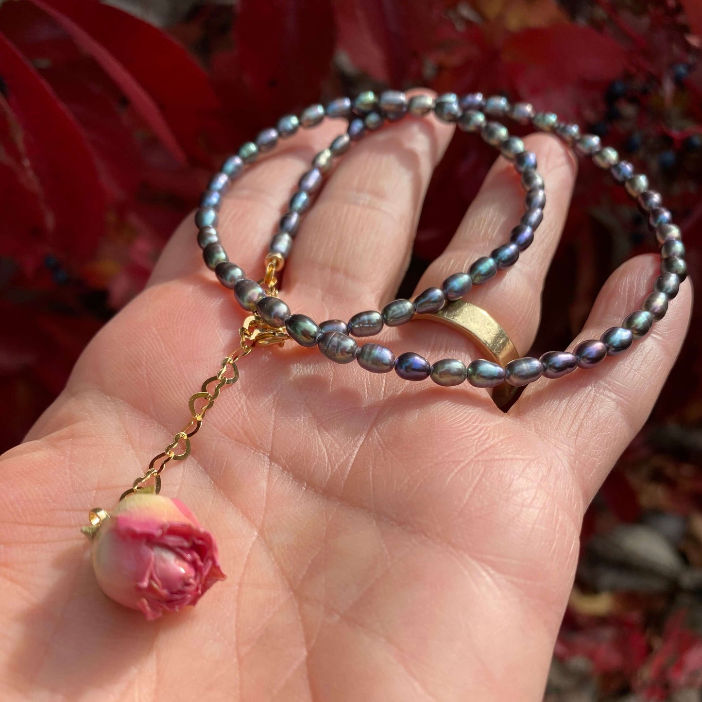 Pink Rosebud Pearl Necklace featuring black rice pearls and a preserved pink rosebud.
