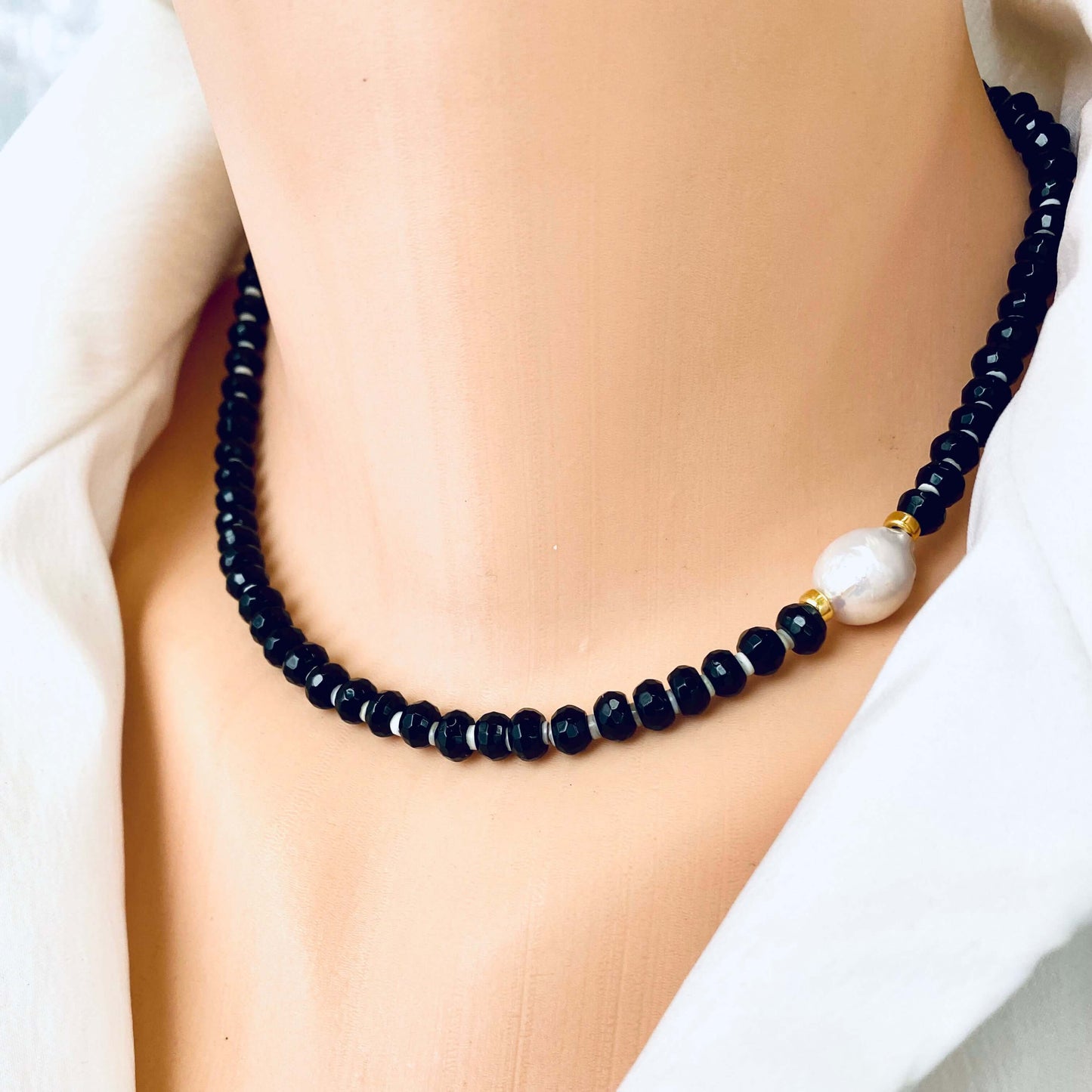 Black onyx pearl choker necklace worn at the neckline with white baroque pearl accent