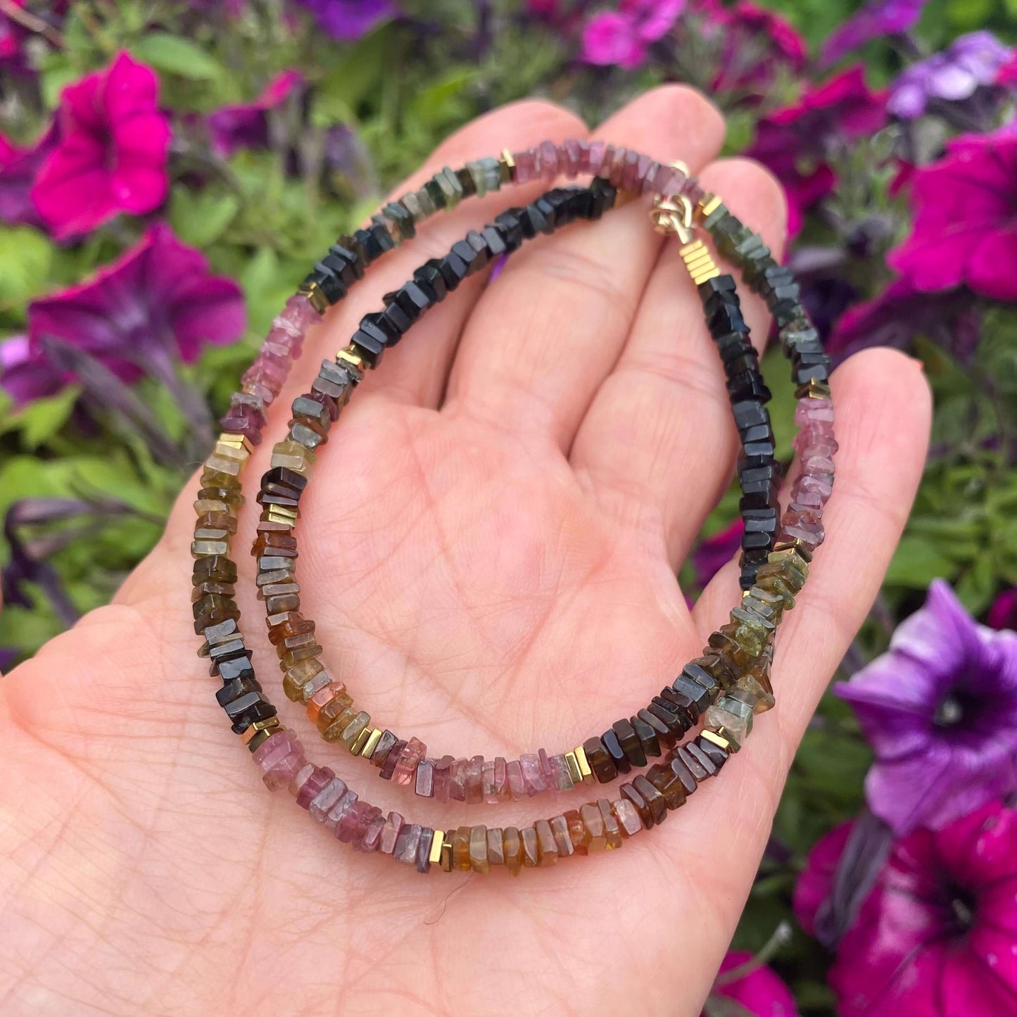 Tourmaline Necklace 14k Gold Filled in hand with purple flowers background, colorful tourmaline beads