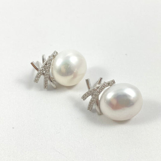 A pair of stud earrings featuring large, lustrous white freshwater pearls set in silver-toned metal with small clear pavé stones, shown on a plain light gray background.