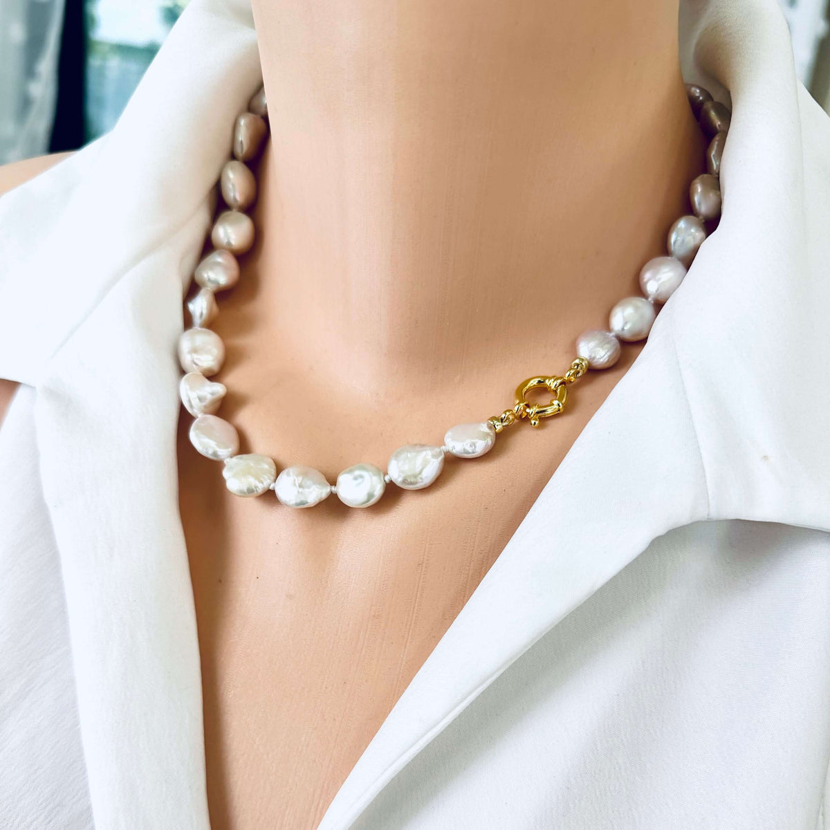 Side close-up of coin pearl necklace with gold clasp worn on mannequin