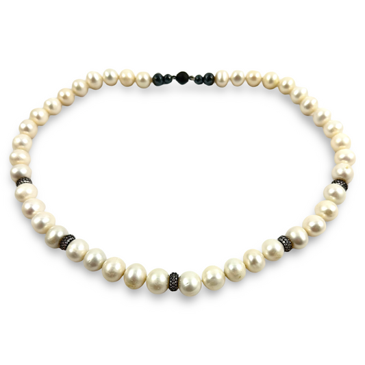 A pearl necklace with large cream-colored freshwater pearls and small dark metallic spacer beads, displayed on a clean white background.