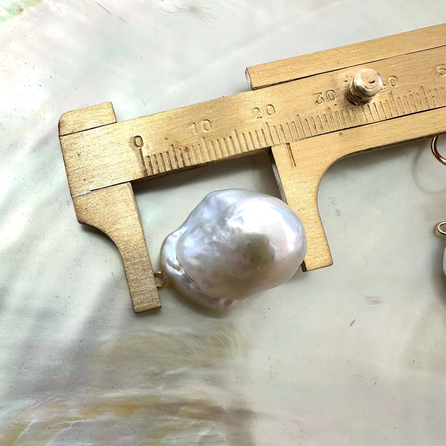 Baroque pearl drops measured against ruler without gold flower studs