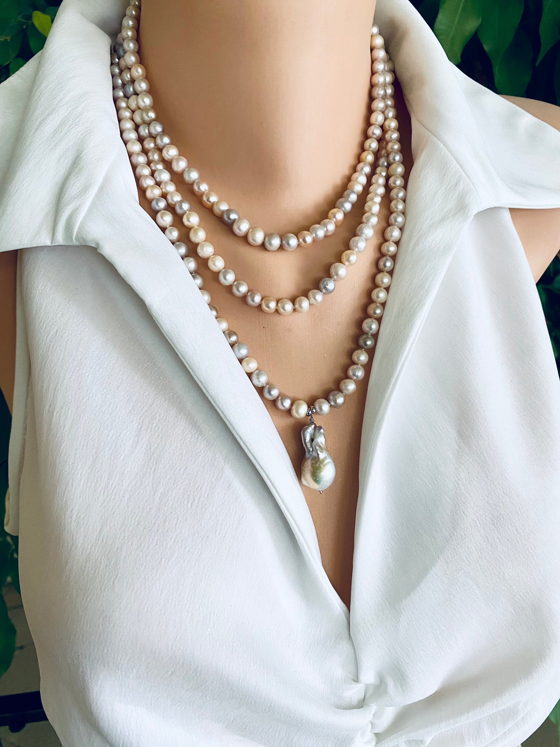 Pearl necklace draped over a white shirt with a blurred background