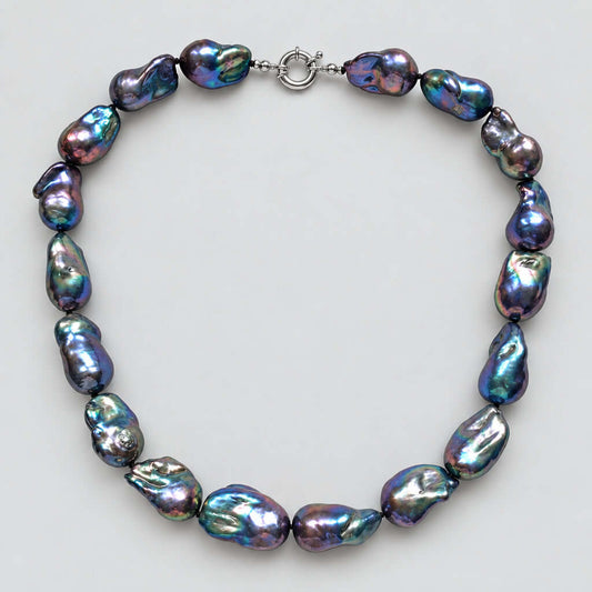 A baroque pearl necklace made of irregular, iridescent beads with a silver clasp, displayed on a plain white background.