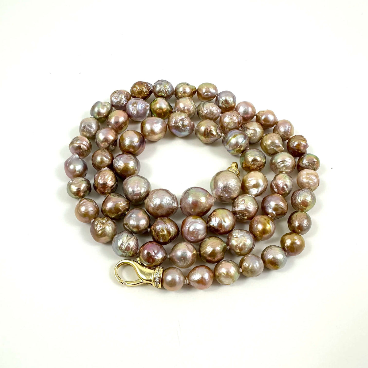 A pearl necklace with irregular, baroque-shaped beads in shades of bronze, brown, and lavender-purple, featuring a gold-tone lobster clasp, photographed on a plain white background.