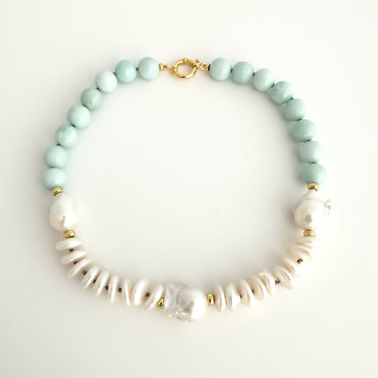 light amazonite green faceted round beads, white baroque pearls, and textured white coin pearls, accented with small gold spacers and a gold clasp, displayed on a light off-white background.
