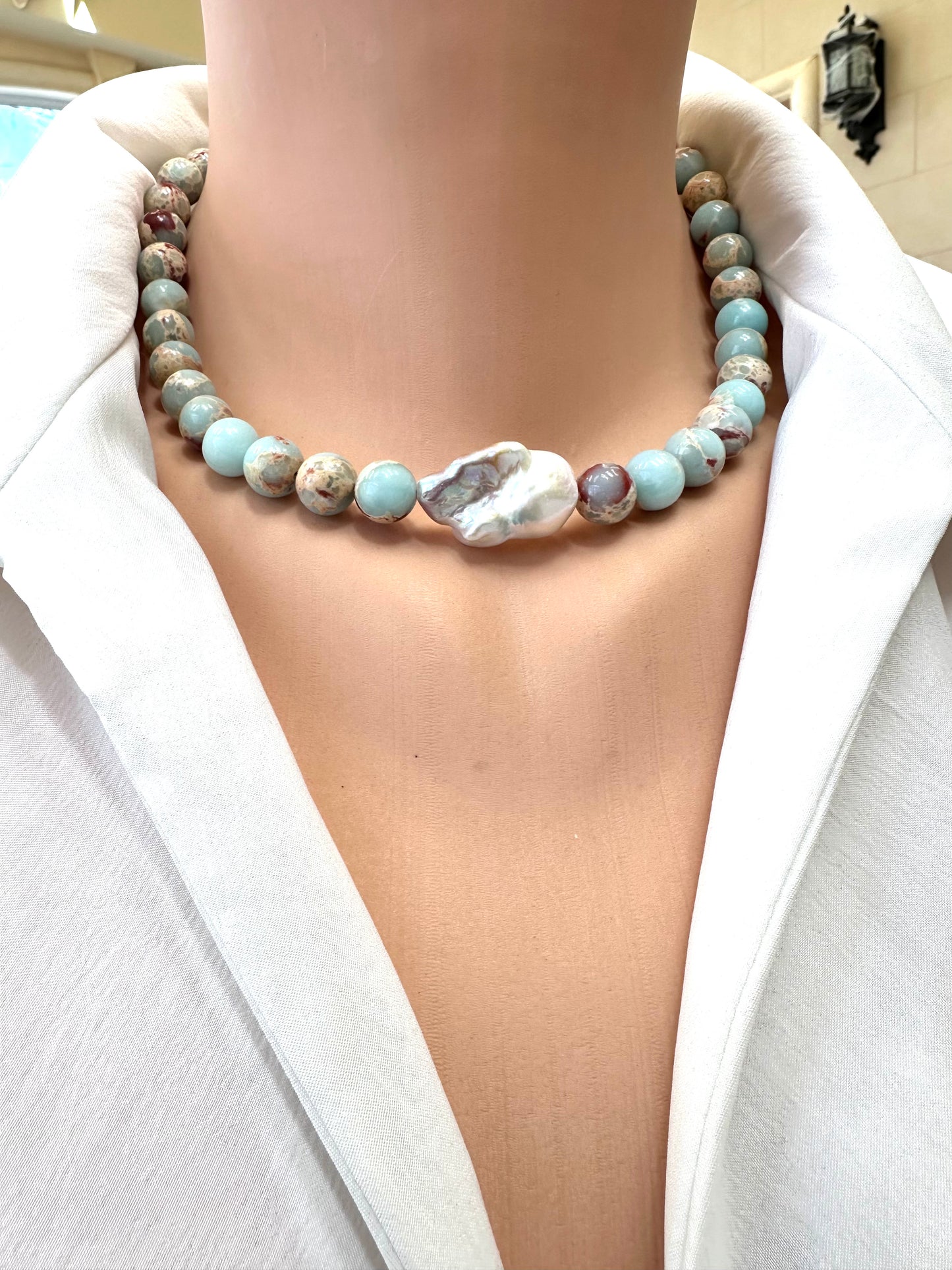 Necklace with multicolored beads and a large shell pendant on a white background