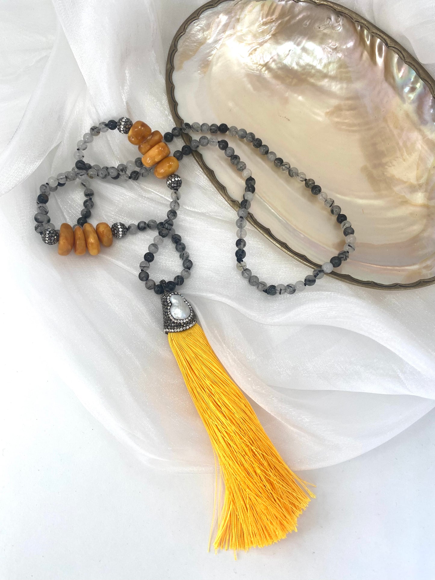 Necklace with yellow tassel and beads on a white fabric background