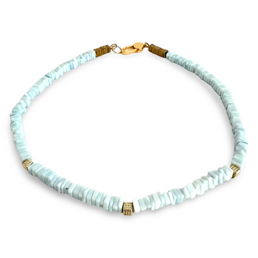A beaded necklace made of light blue-gray polished stone chips with small gold spacer beads and a gold clasp, shown on a plain white background.