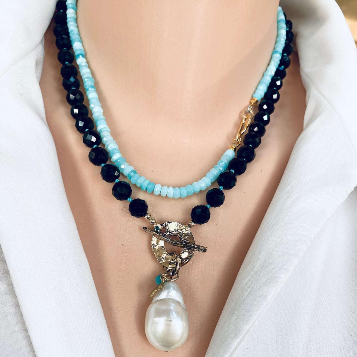 Black tourmaline baroque pearl toggle necklace close-up showing hamsa charm and amazonite accent