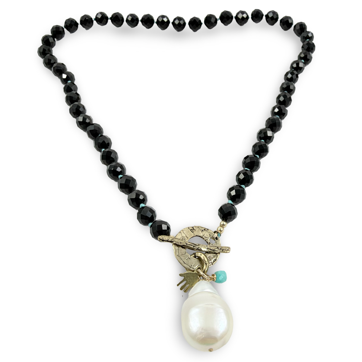 A beaded necklace featuring faceted black beads, a gold-tone toggle clasp, and a large white baroque pearl pendant with a small turquoise accent.