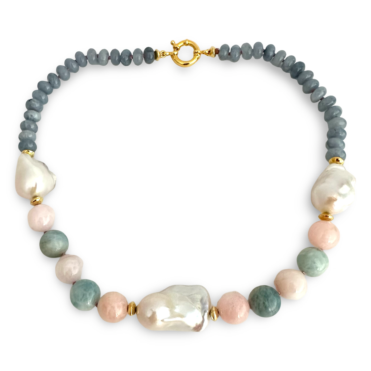 A beaded necklace featuring a strand of slate blue-gray round beads, a large irregular white baroque pearl, several pale pink baroque pearls, and several round sage green baroque pearls, separated by small gold spacer beads and a gold clasp, shown on a plain white background.