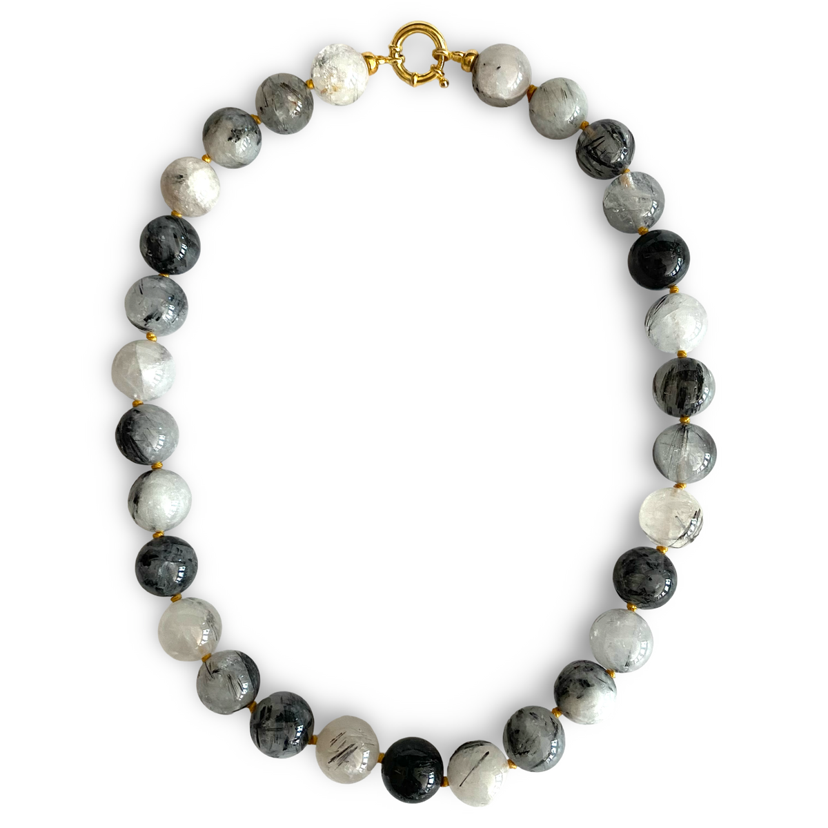 A beaded necklace made of round polished beads in black, white, and gray with natural marbling, separated by small gold spacers and finished with a gold clasp, shown on a plain white background.