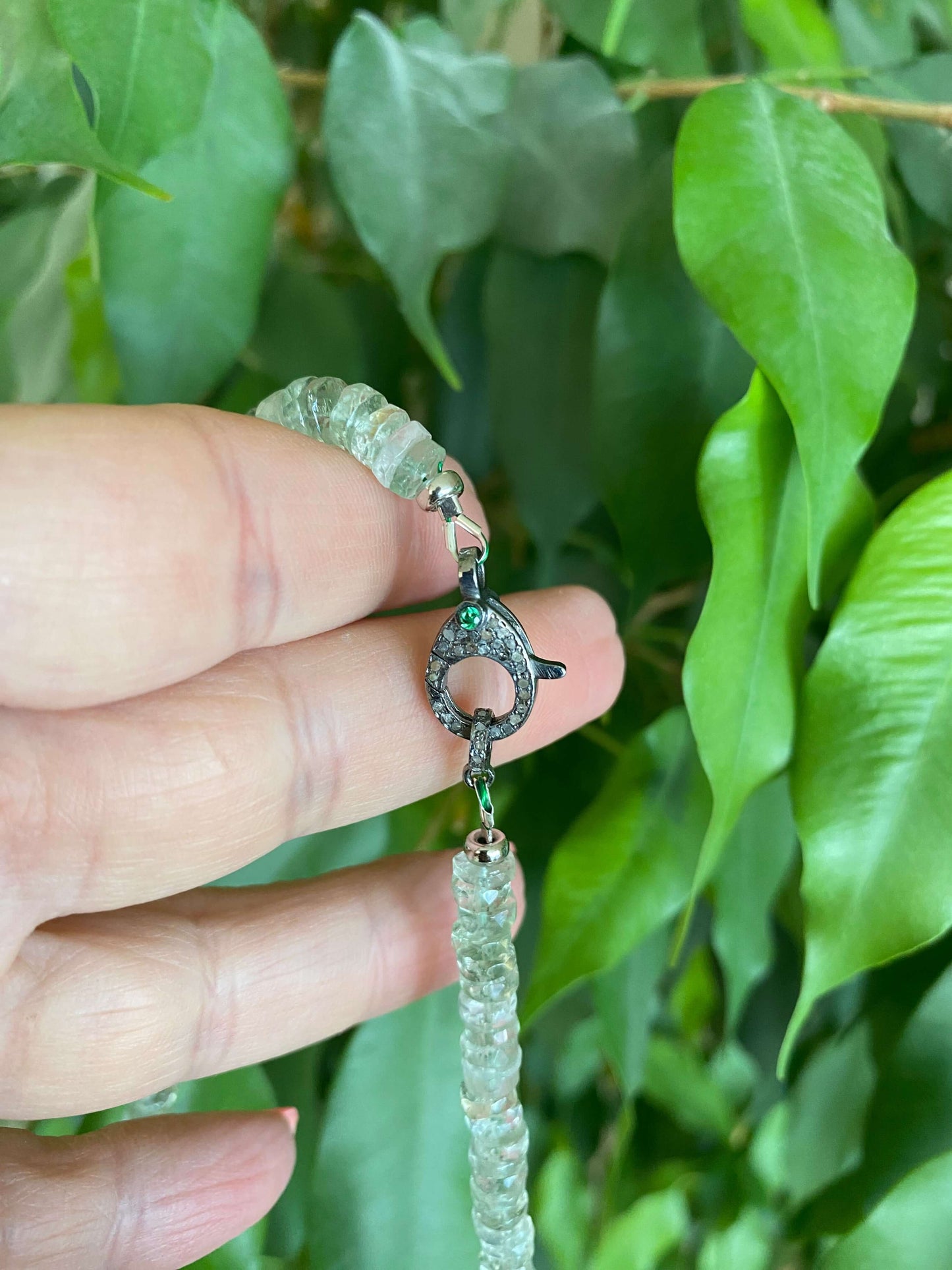 Close-up of green amethyst beaded necklace showcasing diamond and emerald pavé clasp.