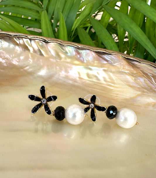 Edison pearl black spinel earrings flat lay on shell dish with greenery, black enamel flower studs and white pearls