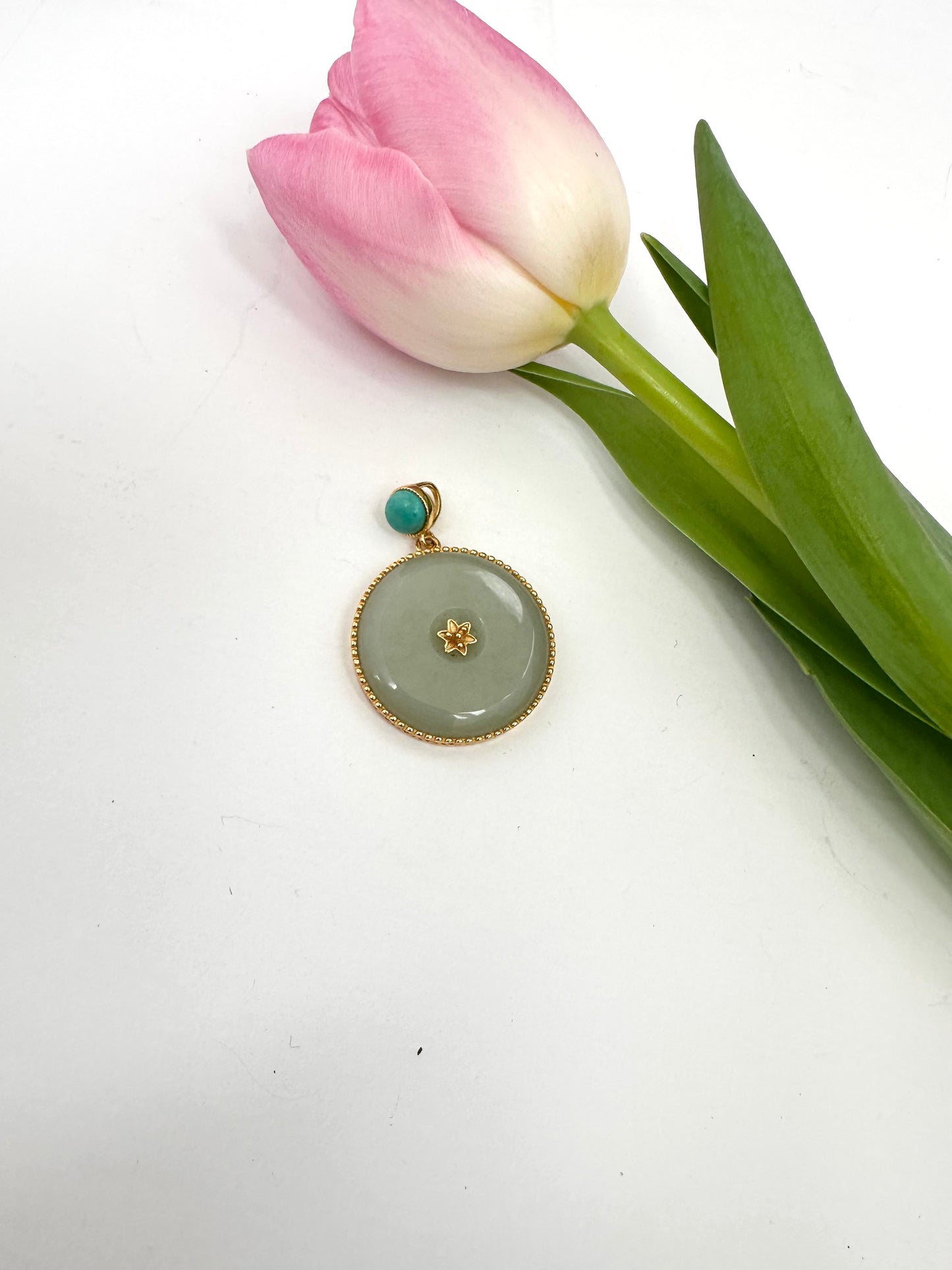 GREEN pendant with turquoise stone and gold accents on a white background with a pink tulip.