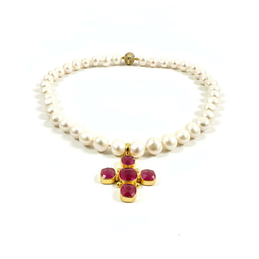 A pearl necklace with a gold cross pendant featuring four faceted magenta-pink gemstones, displayed on a clean white background.