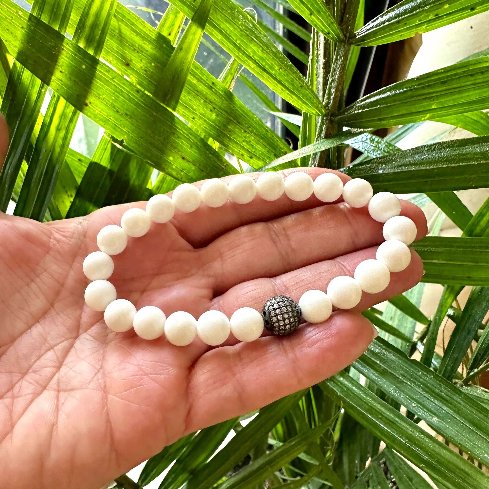 White Tridacna Bracelet held in hand – bead detail in bright natural lighting