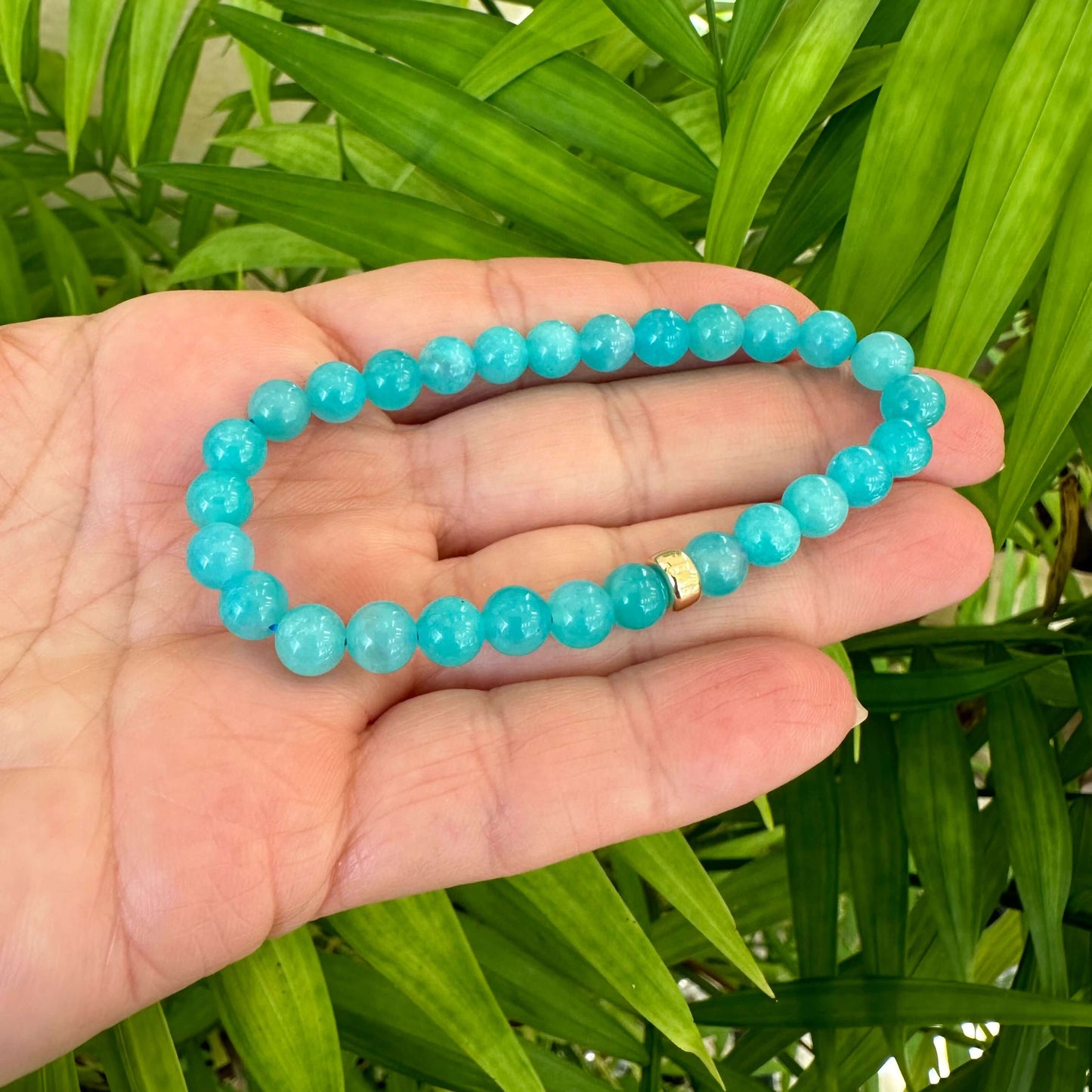 Blue Amazonite Bracelet held in hand against green leaves – outdoor close-up
