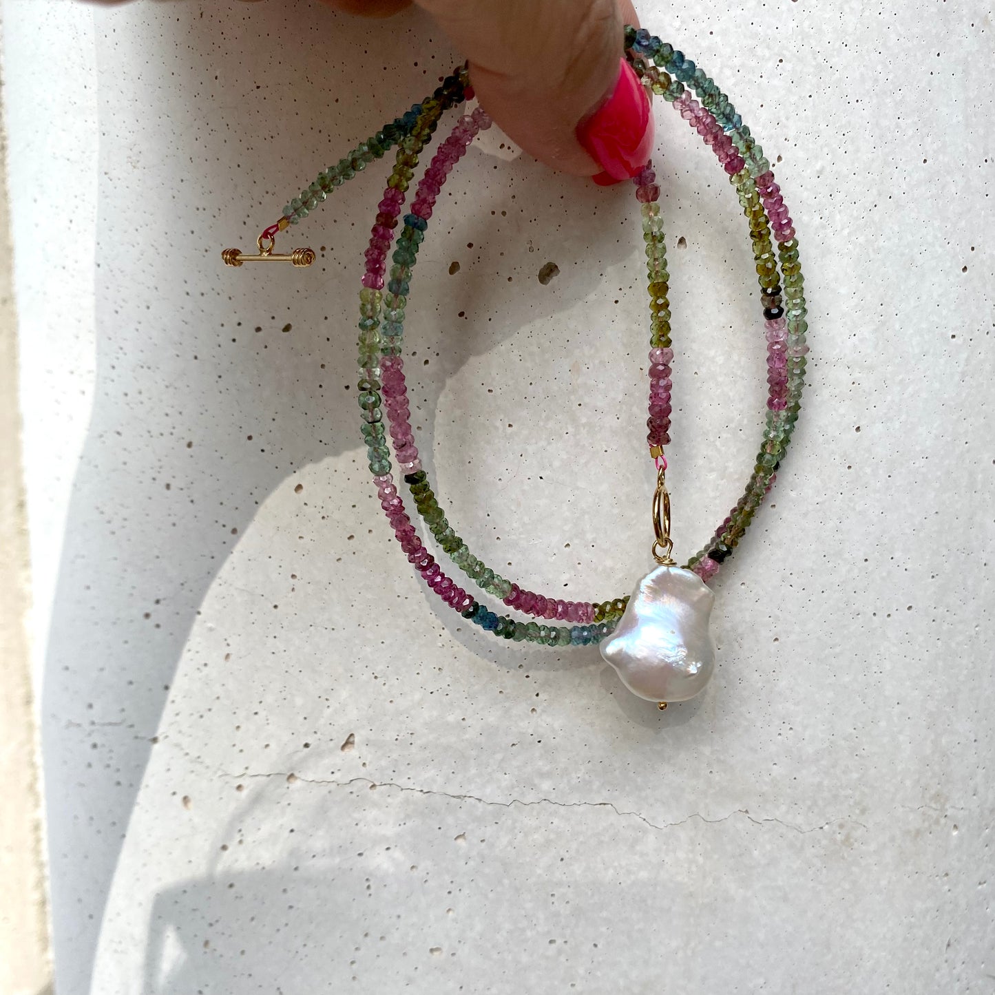 Tourmaline baroque pearl toggle necklace displayed flat showing gemstone strand and pearl charm