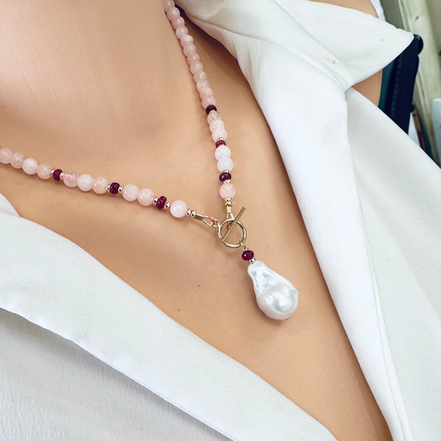 Side close-up of morganite necklace with ruby accents worn on mannequin