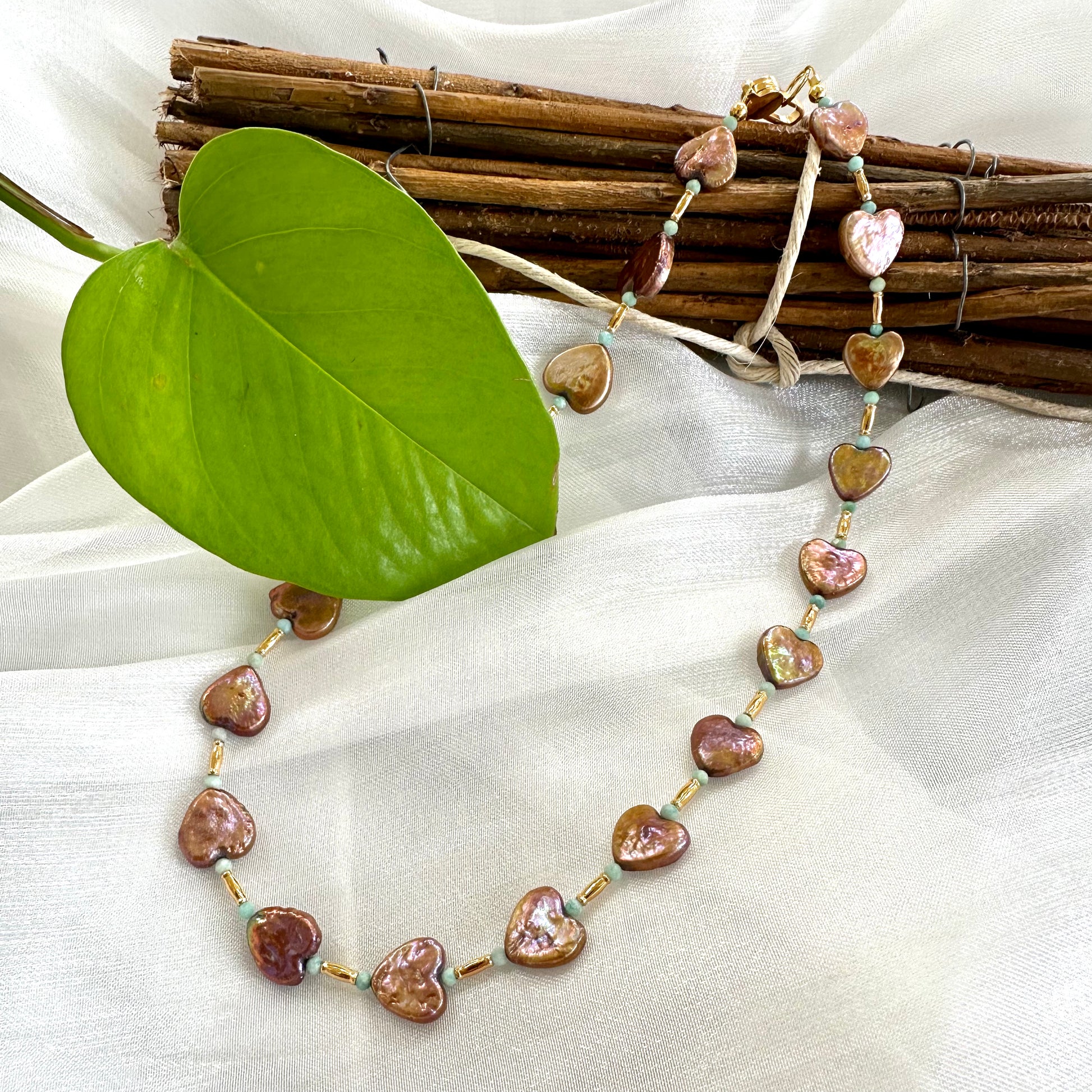 Bronze pearl choker with heart-shaped pearls displayed on white cloth