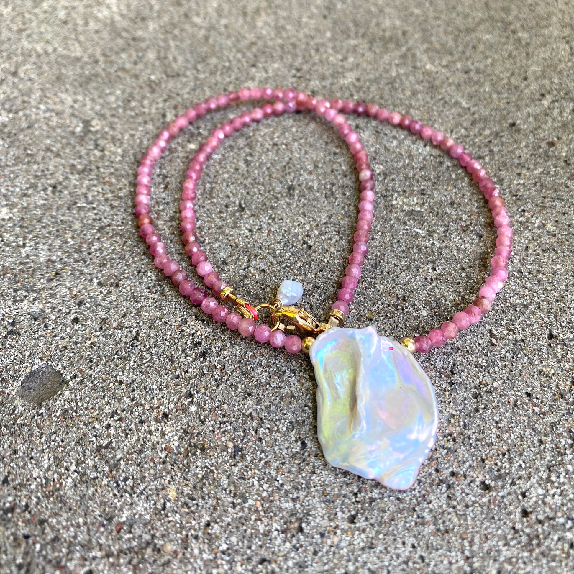 Pink tourmaline keshi pearl choker necklace with gold filled clasp displayed flat