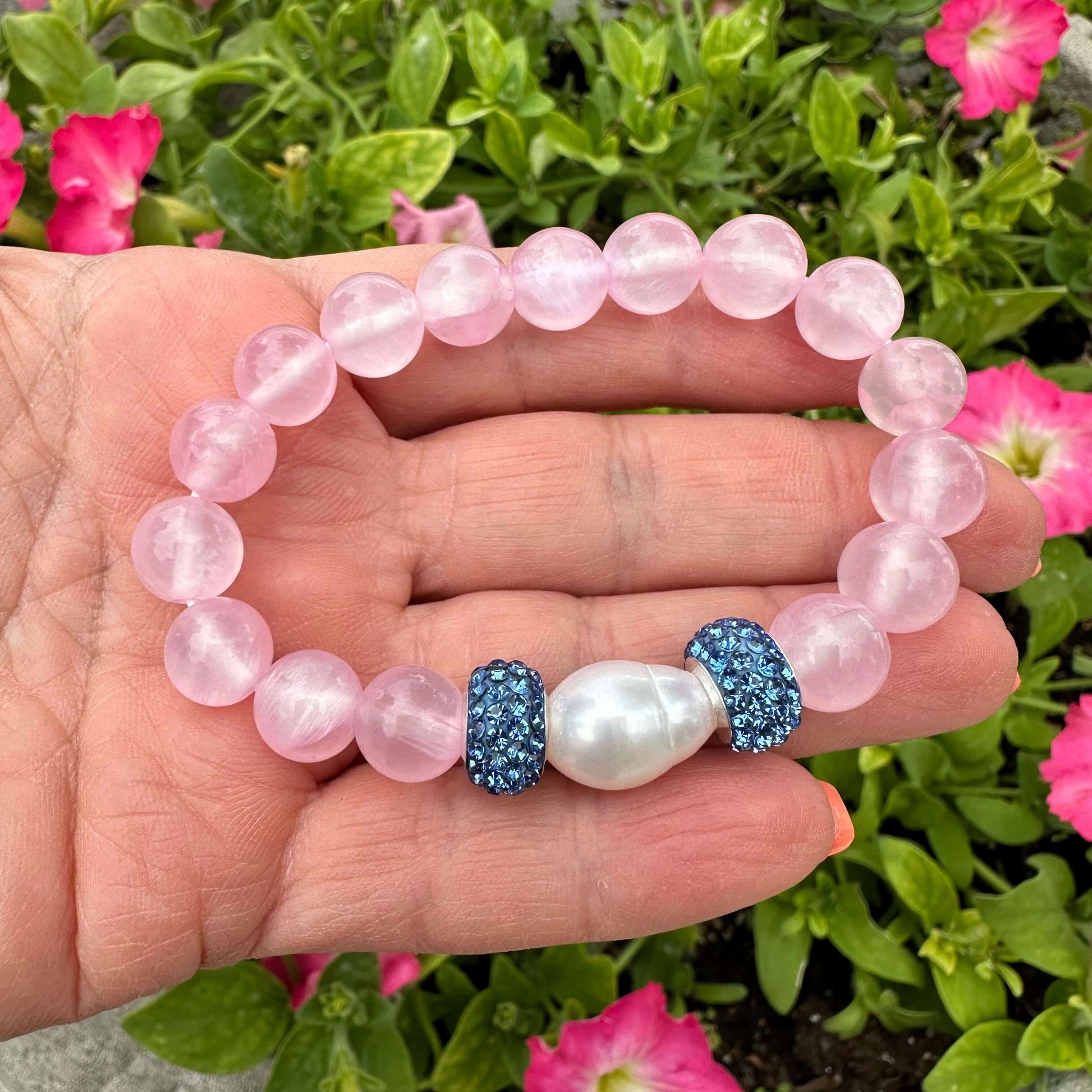 Pink jade bracelet featuring natural 10mm pink jade beads and a freshwater pearl, displayed on a hand.