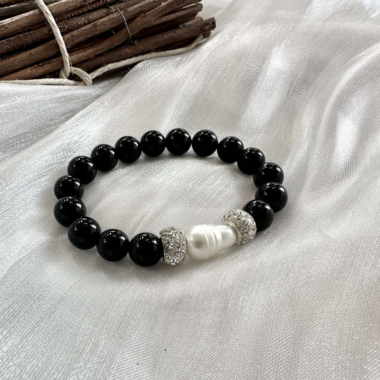 Black onyx bracelet with pearl displayed on white cloth