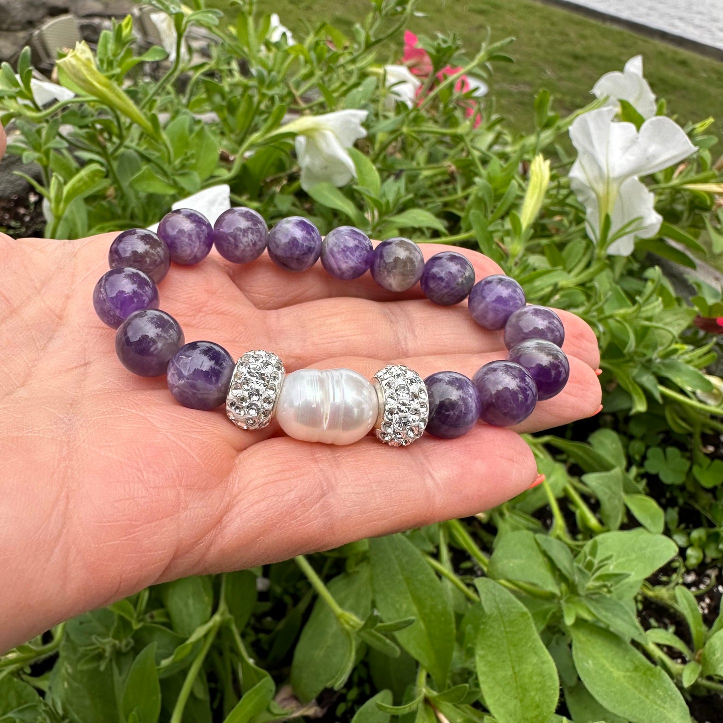 Chevron amethyst bracelet held in hand against green foliage