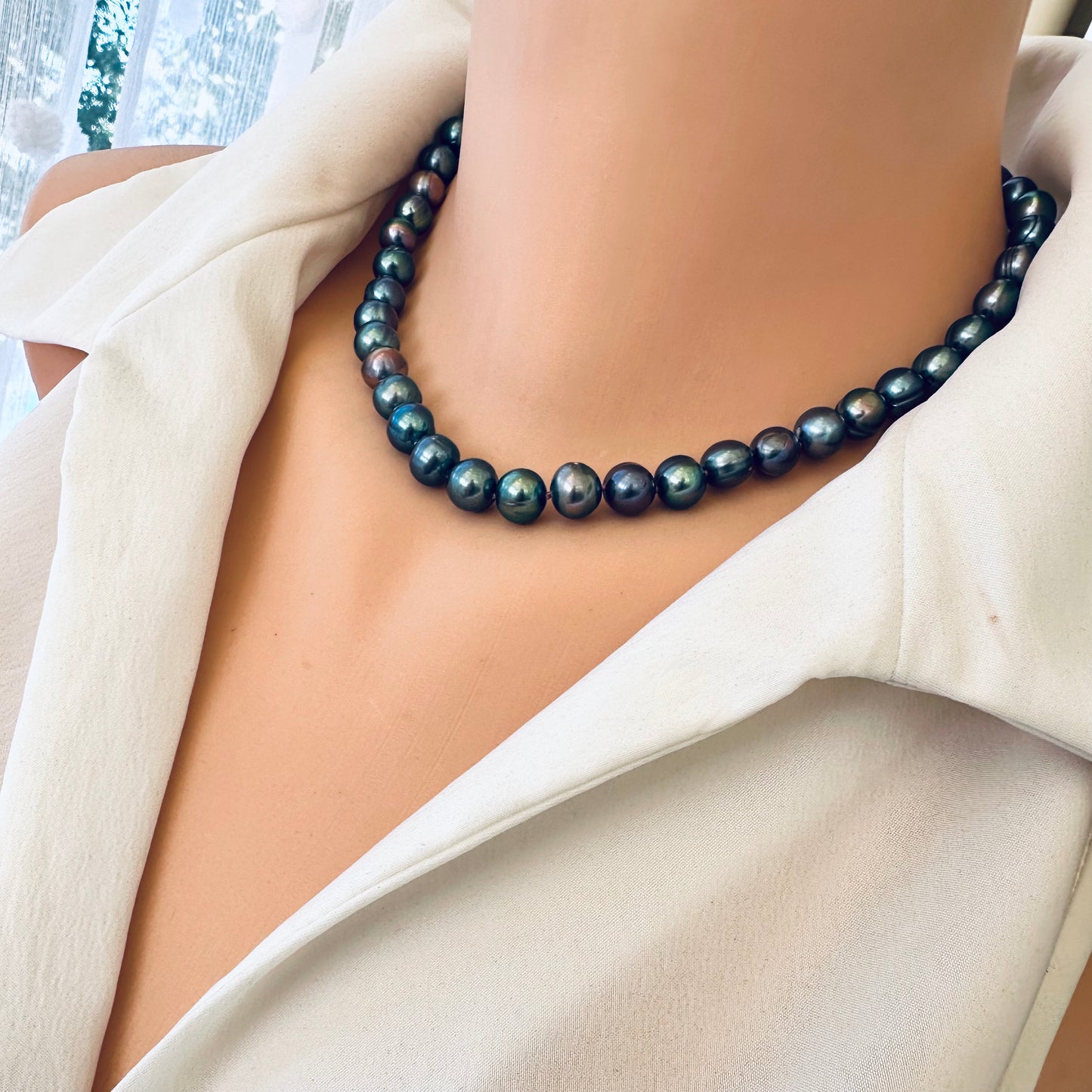 Side close up of peacock pearl necklace worn on mannequin