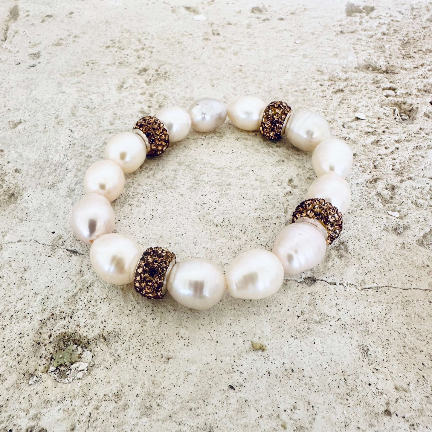 White pearl stretch bracelet with gold rhinestones on white tabletop