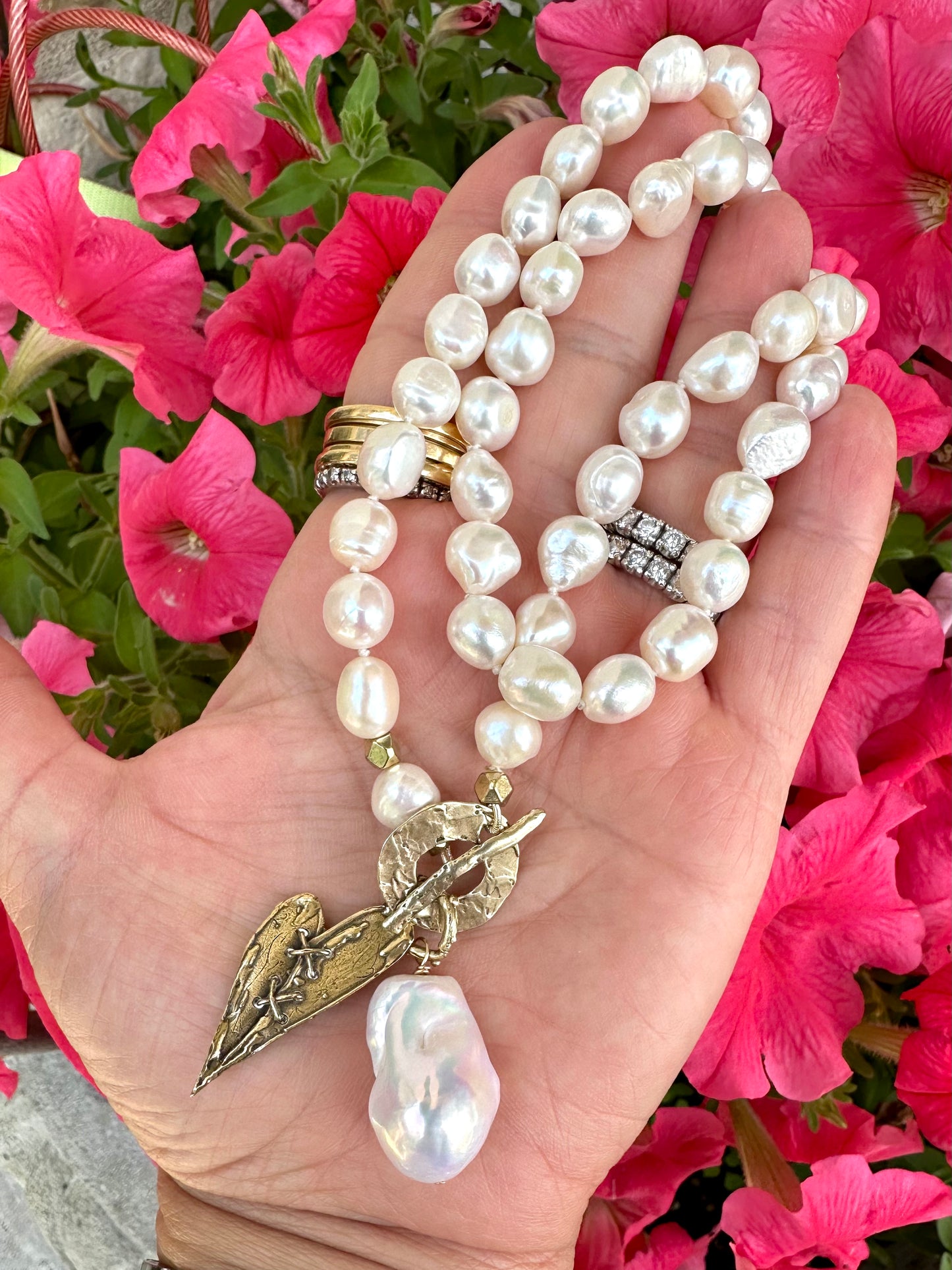 Close-up of pearl toggle necklace with heart pendant held outdoors