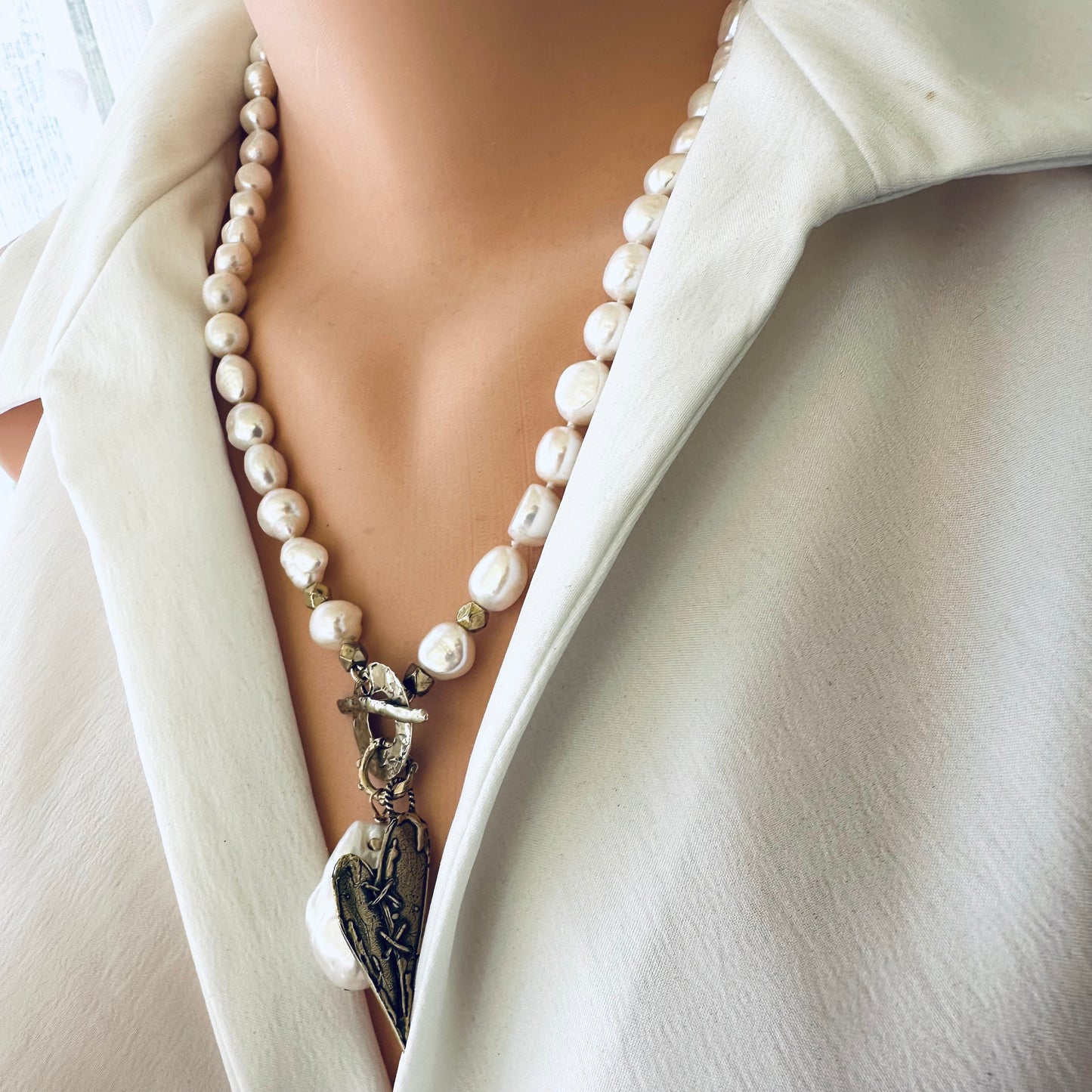 Pearl toggle necklace with heart pendant displayed on mannequin