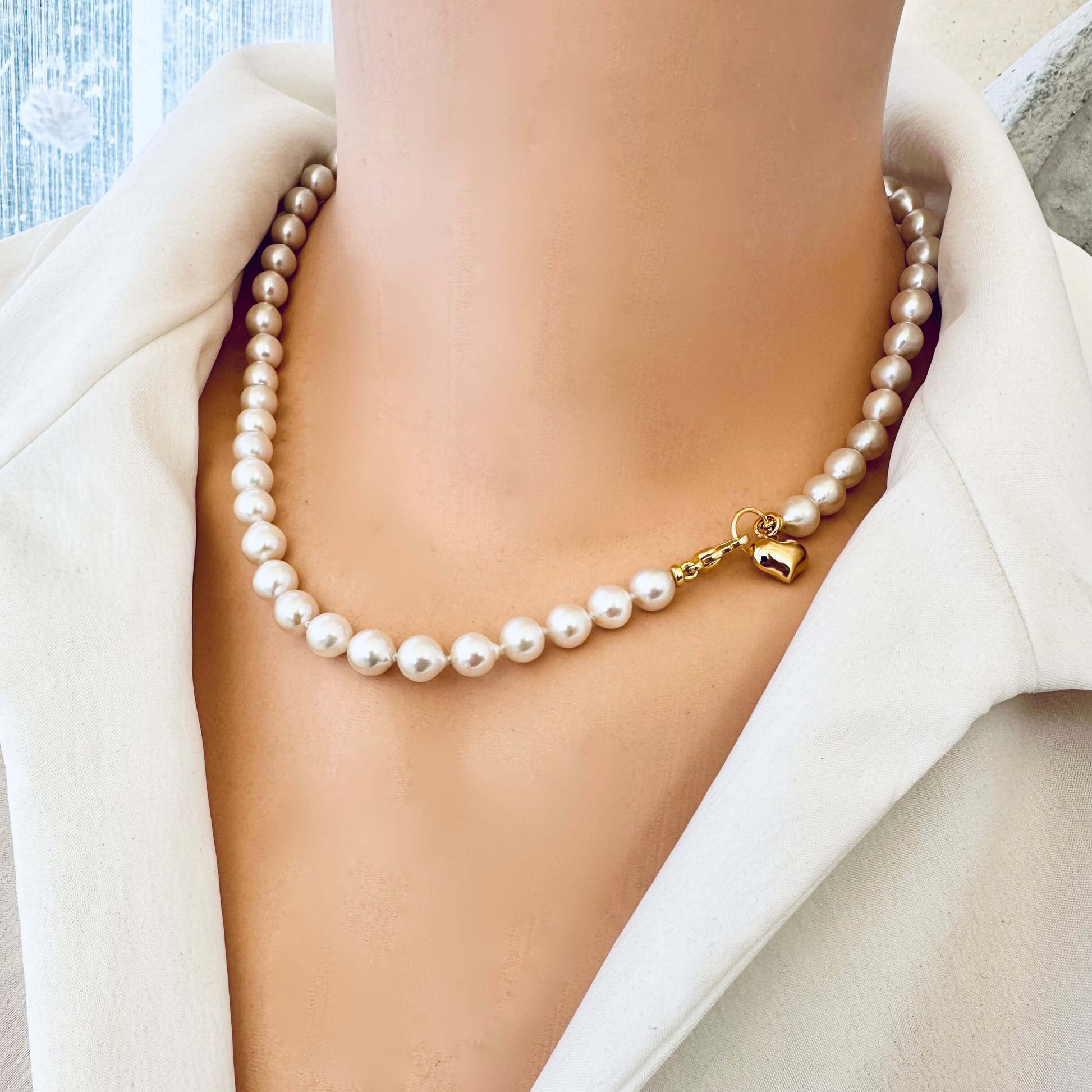 Classic pearl necklace with gold heart charm elegantly displayed on a model, showcasing its timeless beauty.