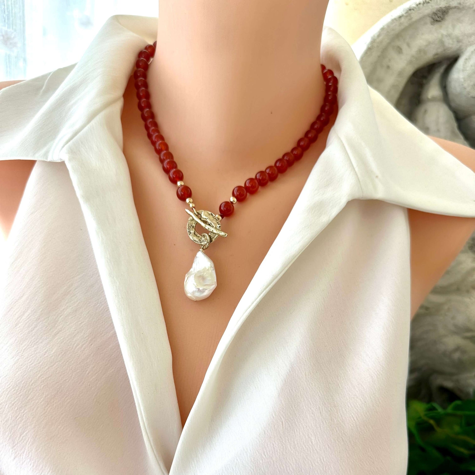 Front close-up of red agate toggle necklace on mannequin with baroque pearl pendant