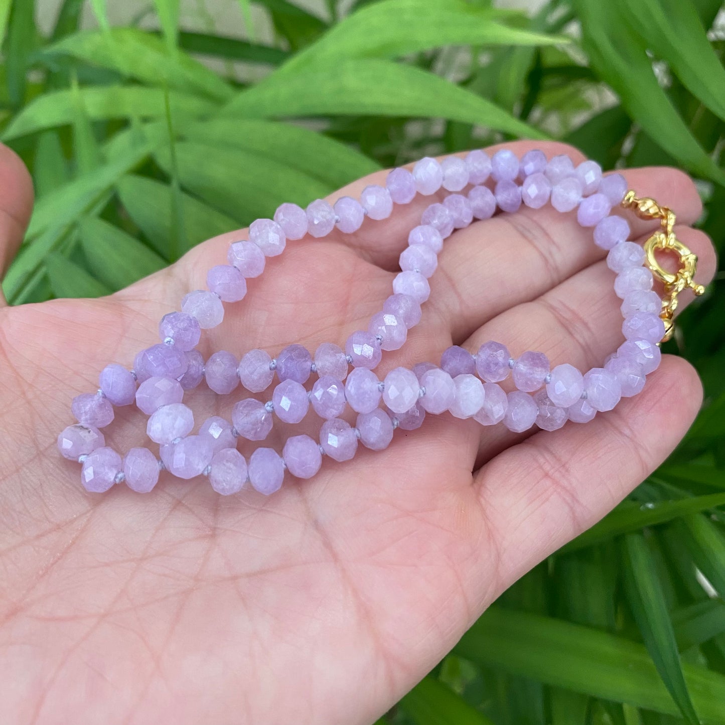 Lavender amethyst baroque pearl necklace displayed against a background of green foliage, capturing its soft purple hues.