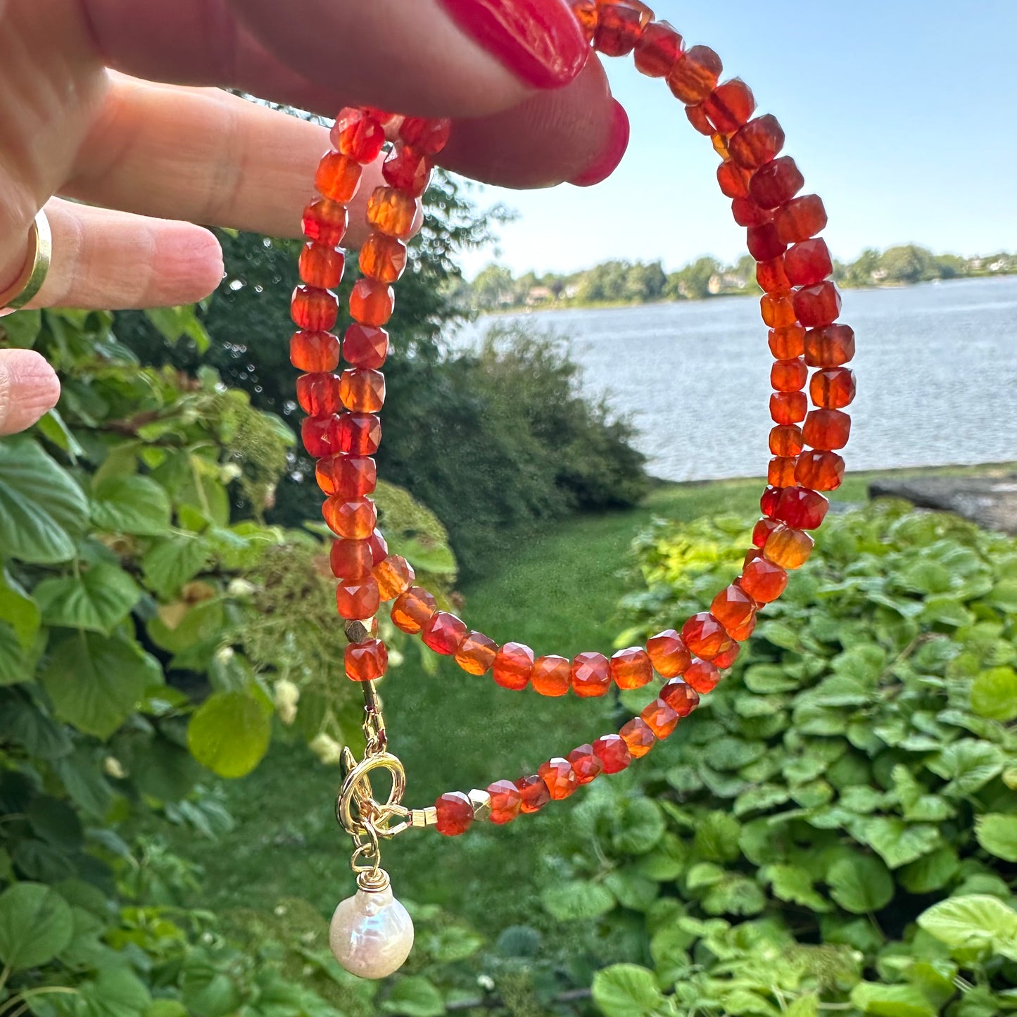 Carnelian toggle necklace with baroque pearl photographed outdoors highlighting warm orange tones