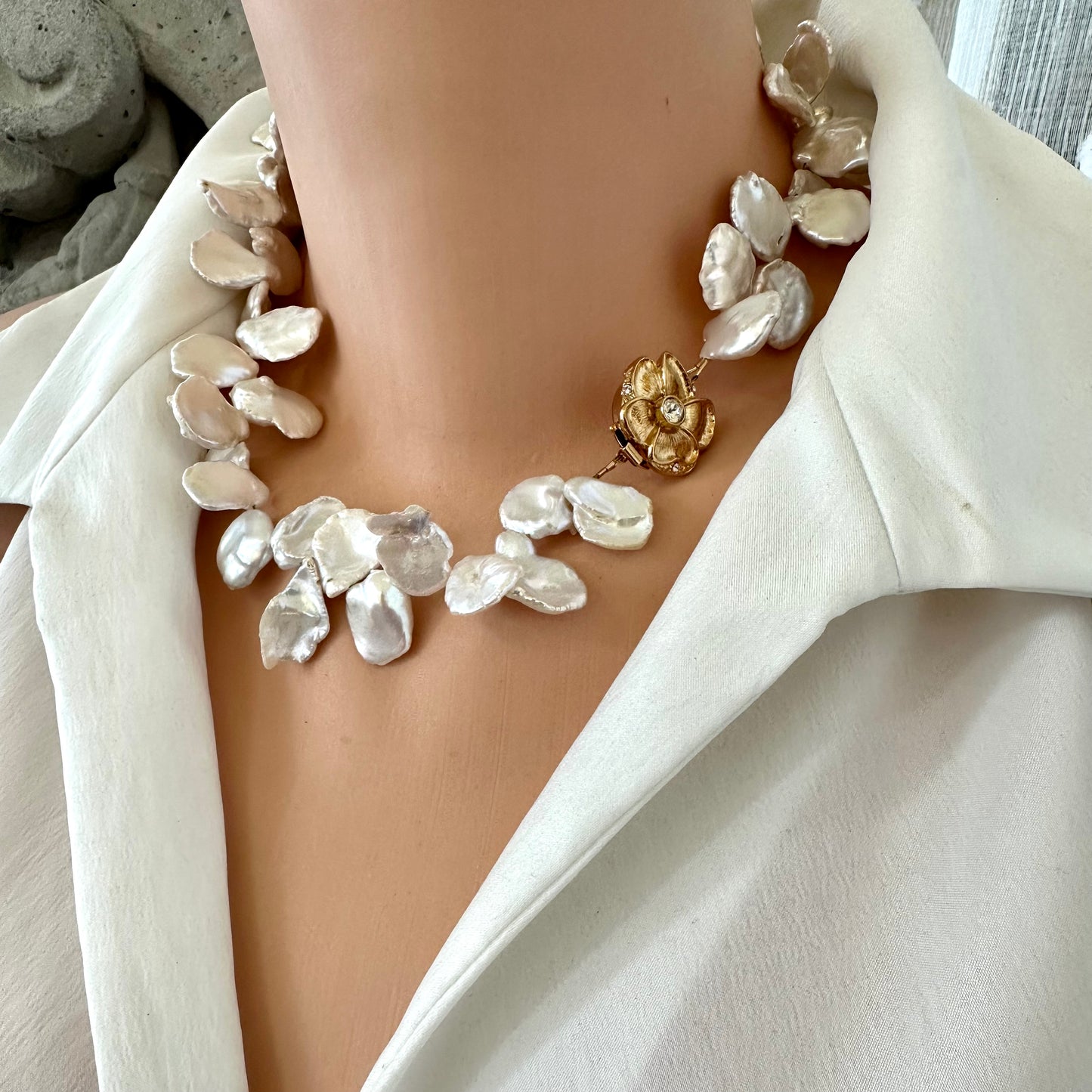 White keshi pearl necklace with flower clasp worn by mannequin, side close-up view