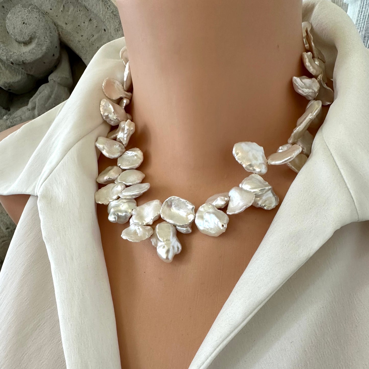 Side view of white keshi pearl necklace with flower clasp displayed on mannequin