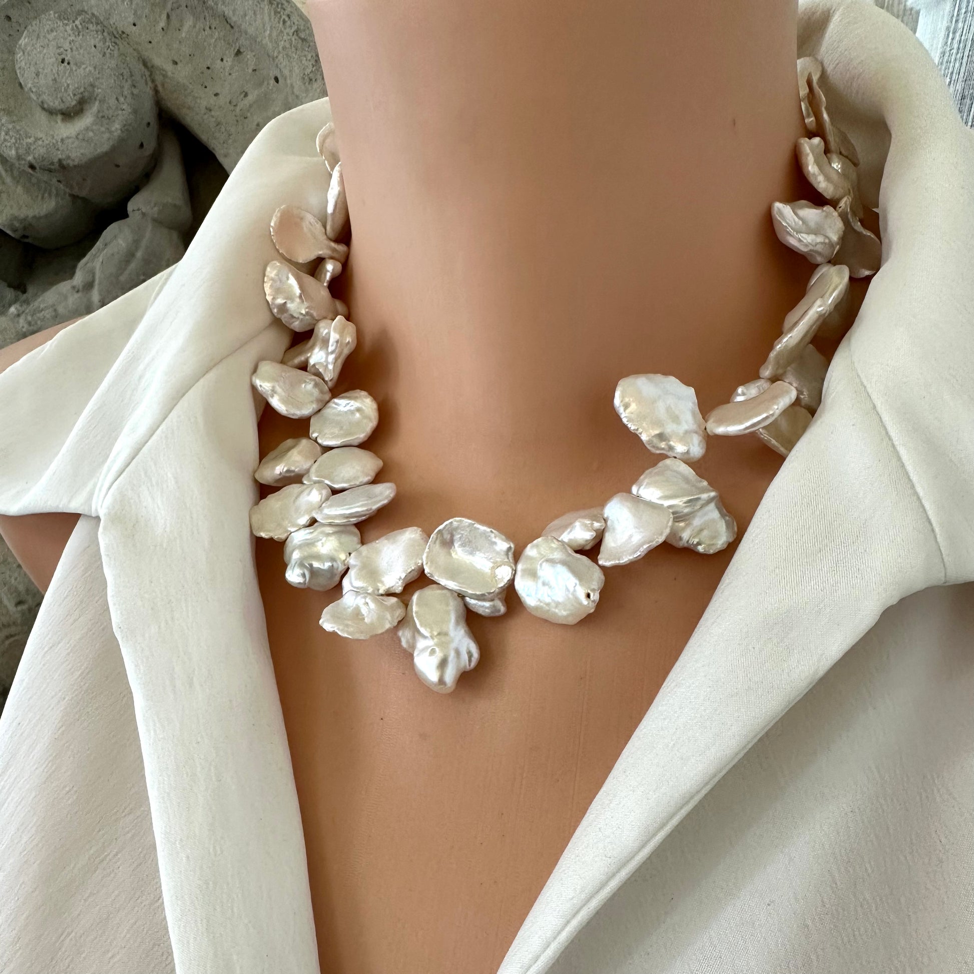 Side view of white keshi pearl necklace with flower clasp displayed on mannequin